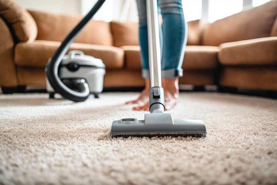 Person using a vacuum cleaner on a carpet in a living room but wants a pet hair vacuum attachment
